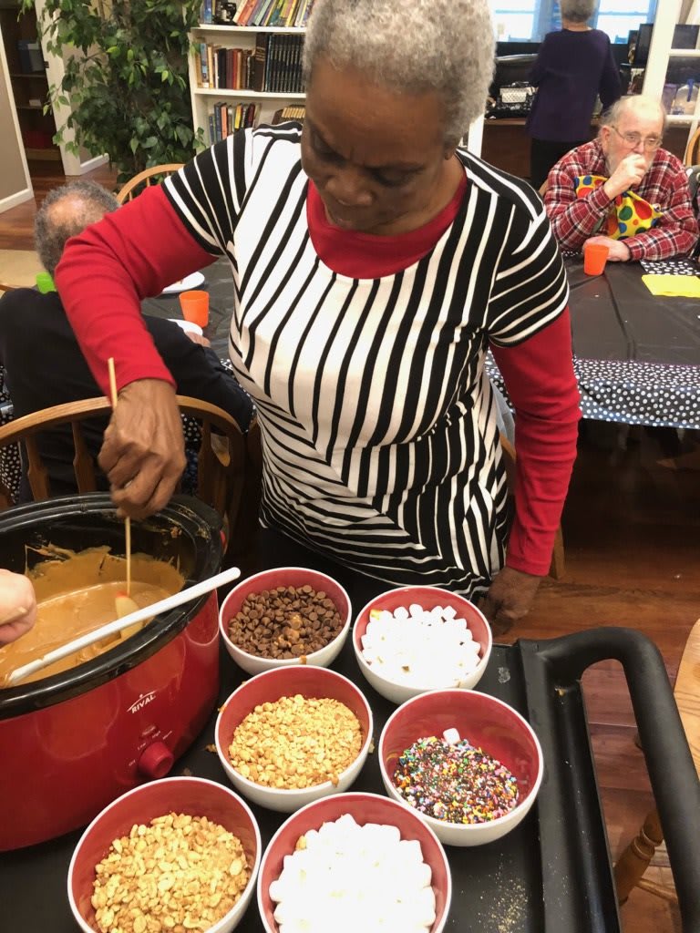A woman prepares a fondue with an assortment of toppings at a buffet.
