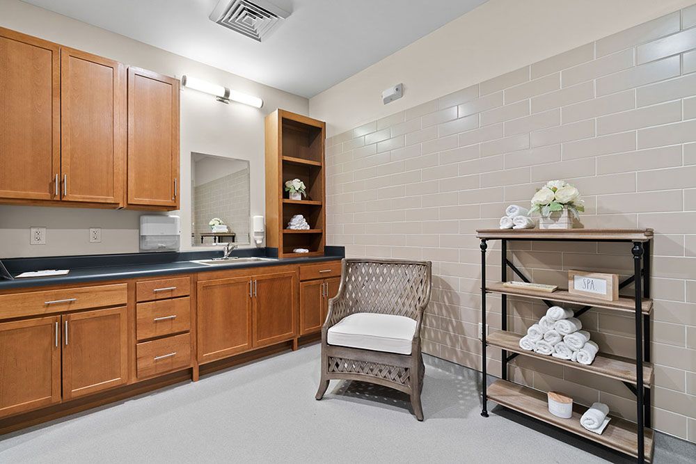 A well-organized bathroom with wooden cabinets, a wicker chair, and neatly arranged towels on shelves.