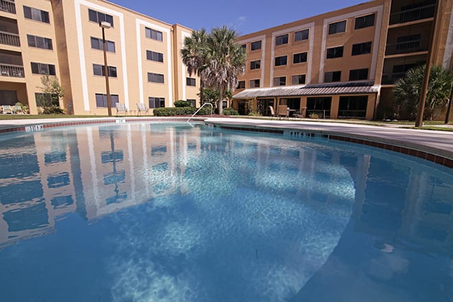 A hotel with a large outdoor swimming pool reflecting the building.