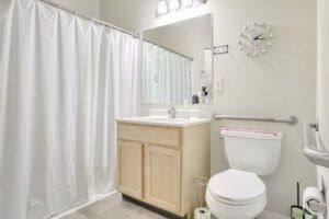 A modern and clean bathroom with a sink, mirror, toilet, and shower curtain.