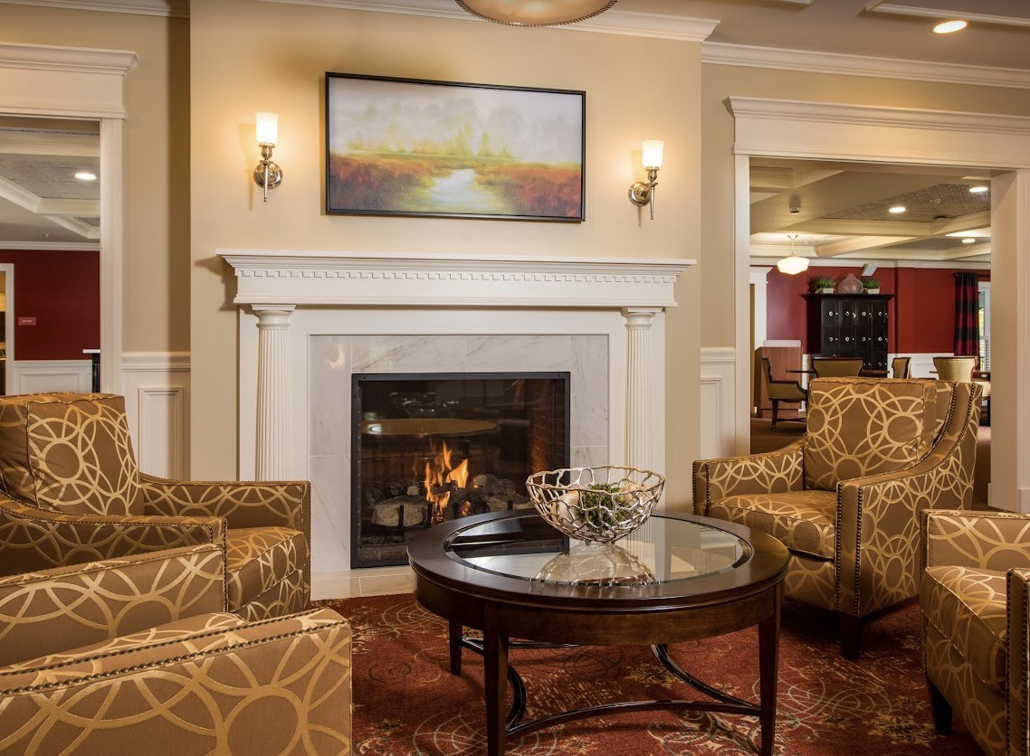 A cozy living room with a fireplace, comfortable seating, and warm lighting.