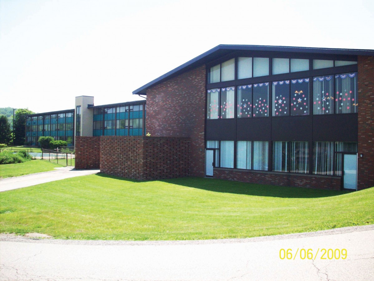 A modern brick building with large windows and a well-maintained lawn under a clear sky.