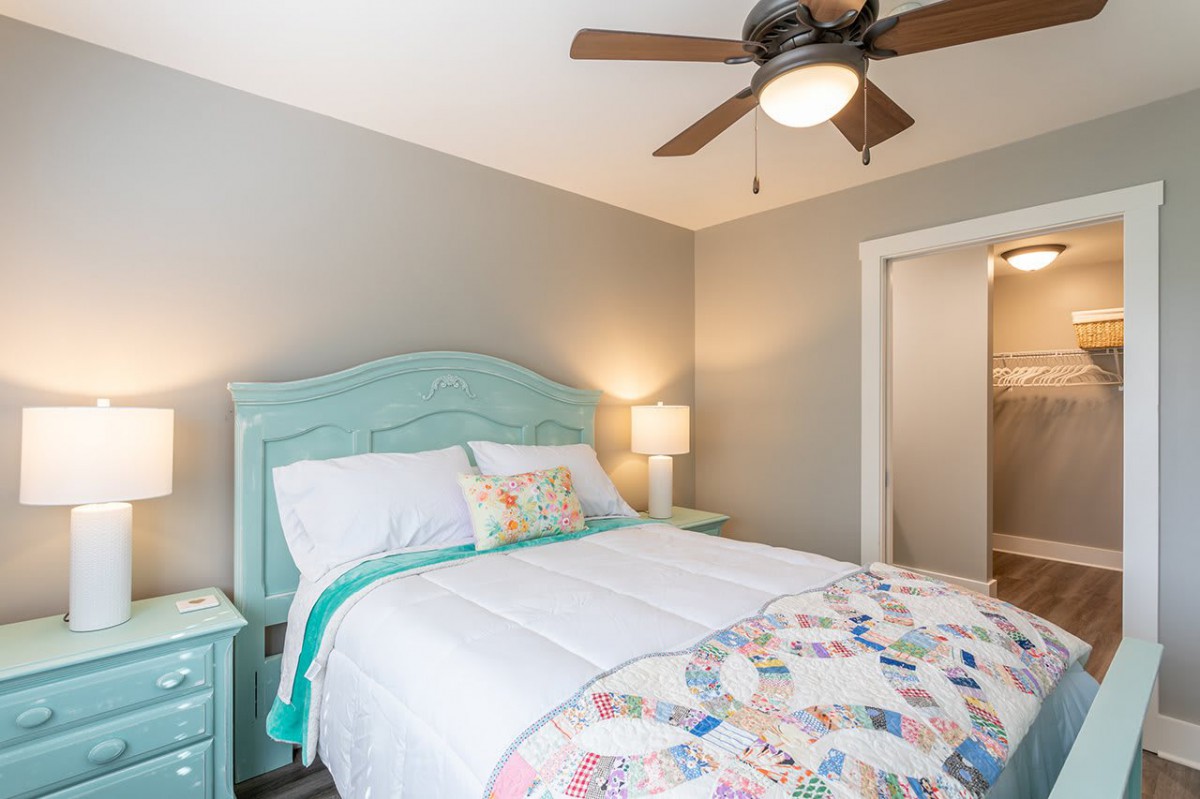 A cozy bedroom with pastel-colored furniture and a quilted bedspread.
