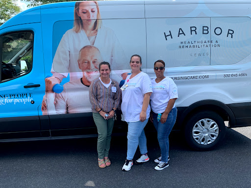 Three individuals posing in front of a branded healthcare van.