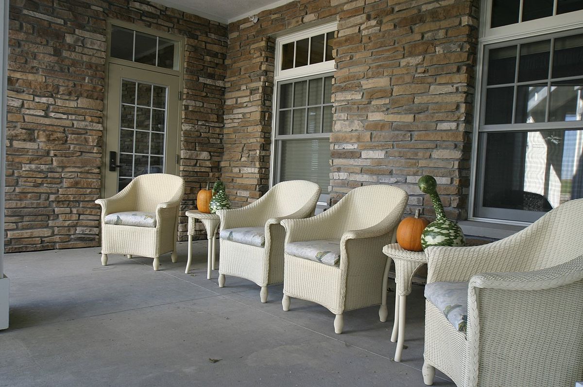 A cozy porch with wicker chairs and autumn decorations, including pumpkins and gourds.