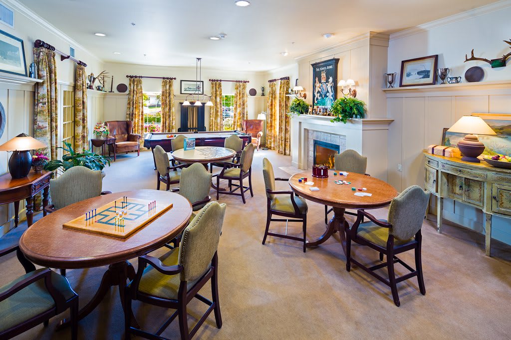 A cozy living room with several tables and chairs, a fireplace, and elegant decor.