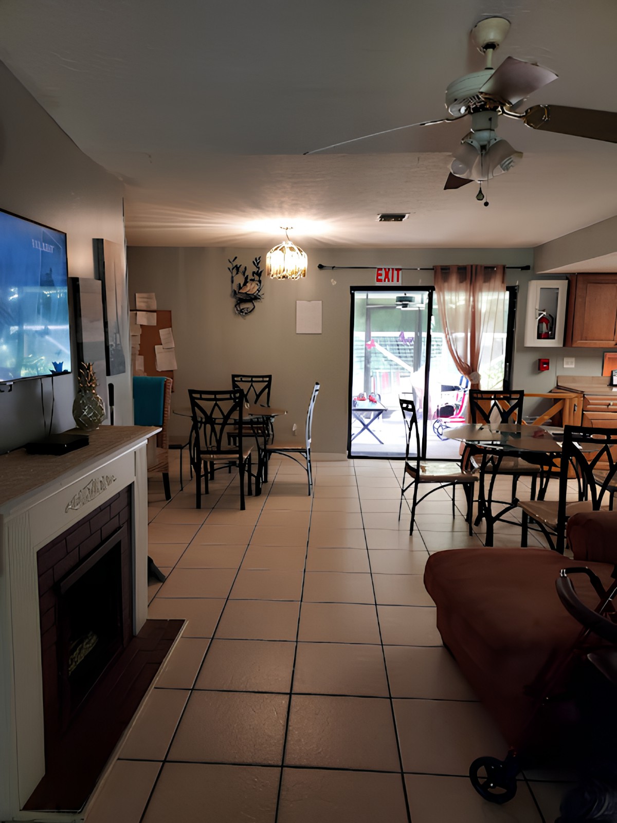 A cozy living space with a connected dining area and kitchen, featuring a television, fireplace, and ceiling fan.