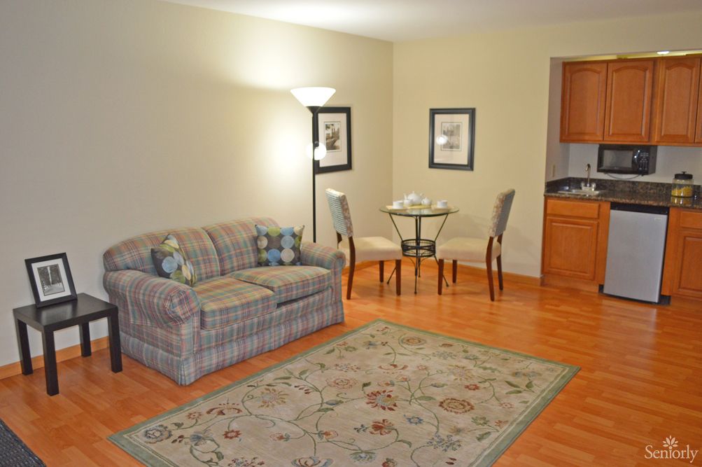 A cozy living room with a sofa, small dining area, and a lamp for lighting.
