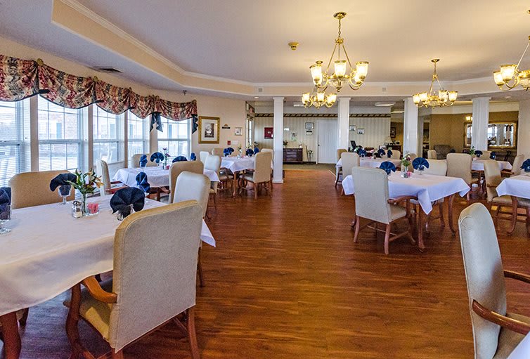 An elegant and spacious dining room with neatly arranged tables and chairs, adorned with chandeliers.