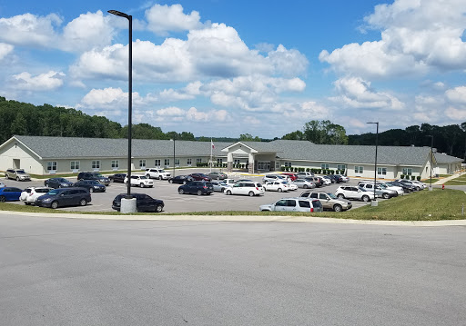 A view of a commercial building surrounded by a parking lot filled with vehicles under a partly cloudy sky.