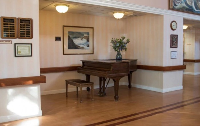 A cozy corner featuring a grand piano, artwork, and floral arrangement.