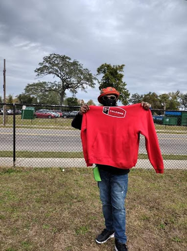 A person showcasing a red hoodie against an outdoor background.
