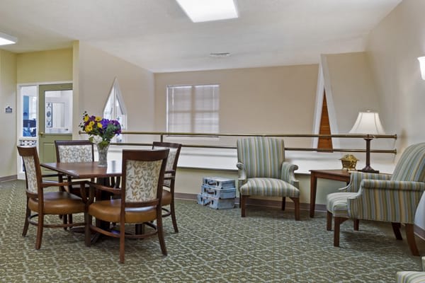 A cozy sitting area with a table, chairs, and a flower arrangement by the window.