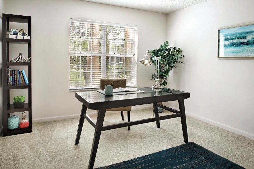 A minimalist home office with a modern desk, chair, and a green plant by the window.