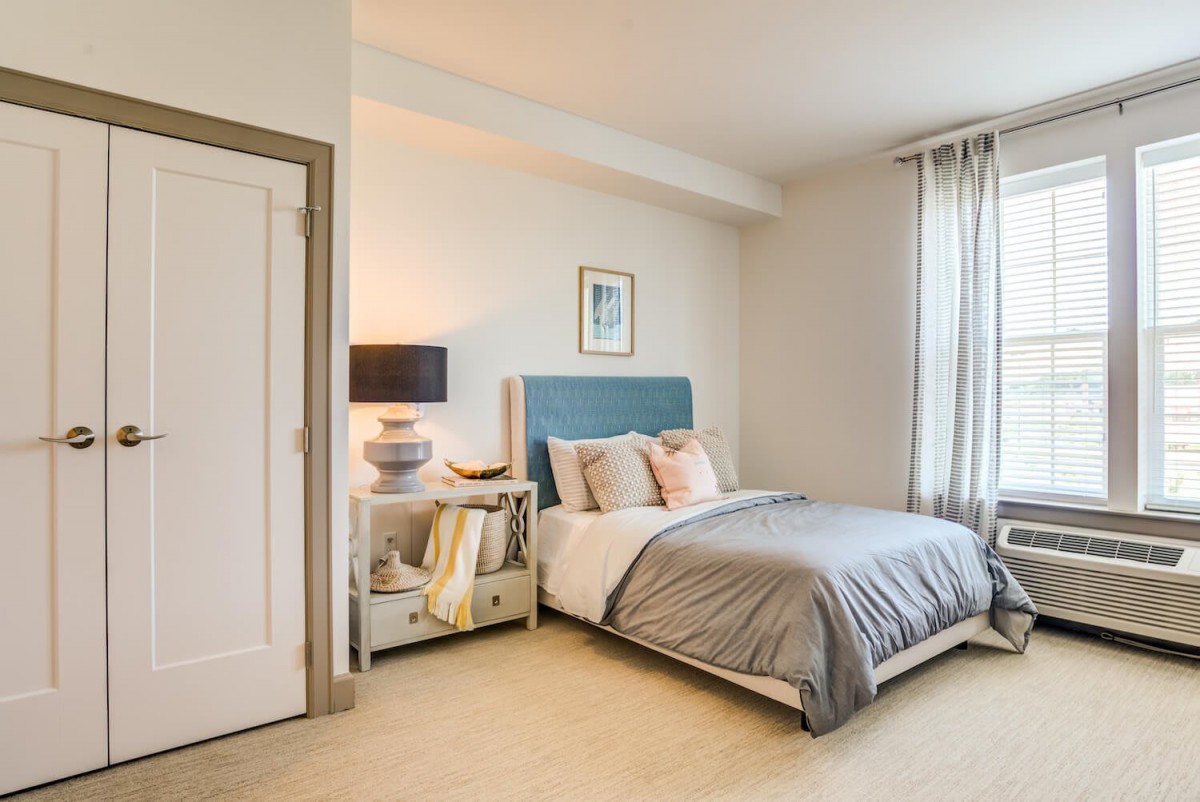 A cozy and modern bedroom with a neatly made bed, nightstand, and lamp.