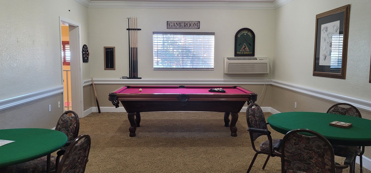 A cozy game room with a pool table and cue sticks on display.