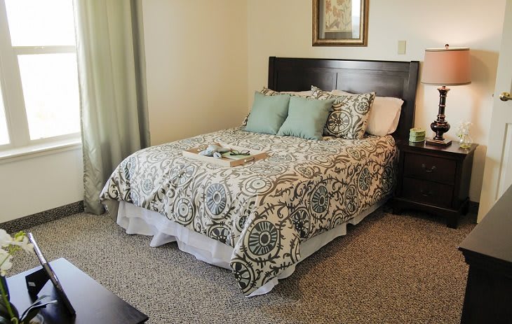 A cozy bedroom with a neatly made bed and decorative pillows.