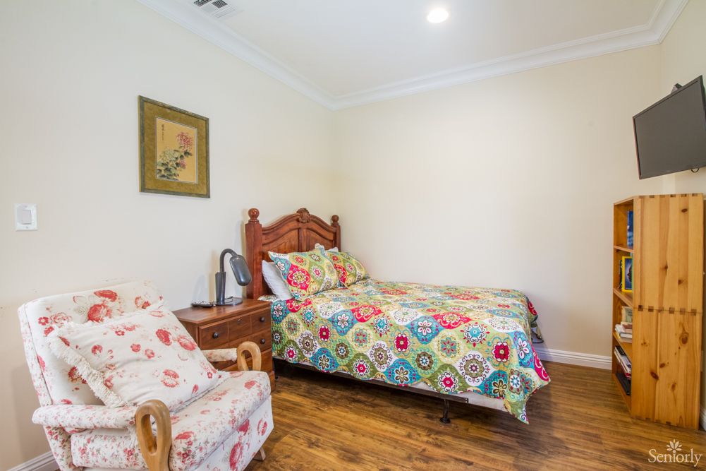 A cozy bedroom with a single bed adorned with colorful bedding and wooden furniture.