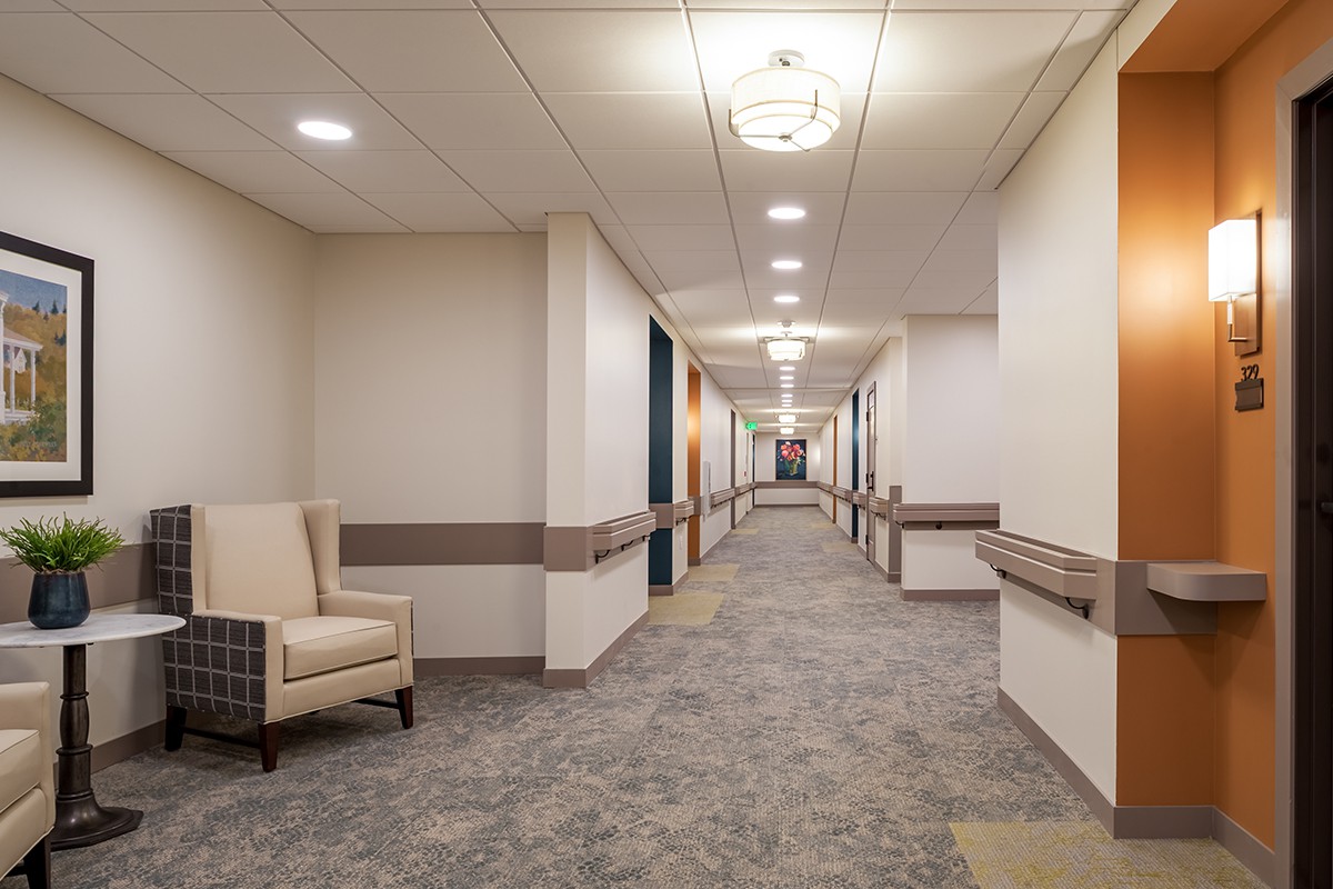 A well-lit, modern hallway with a comfortable chair placed against the wall.