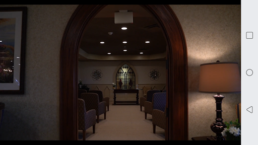 A serene waiting room viewed through an arched doorway, featuring rows of chairs and soft lighting.