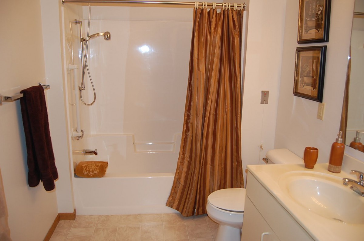 A clean and tidy bathroom with a bathtub, shower curtain, toilet, and sink.