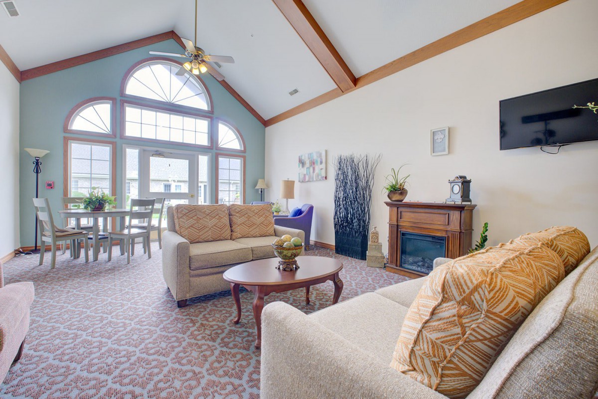 A spacious living room with vaulted ceilings, featuring comfortable sofas, a coffee table, and a fireplace.