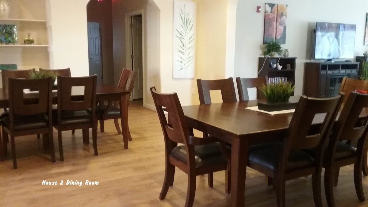 A cozy dining area with wooden tables and chairs, featuring warm lighting and elegant decor.
