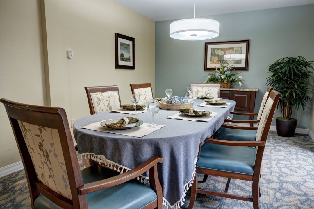 A well-appointed dining room with a table set for a meal, featuring elegant chairs and soft lighting.