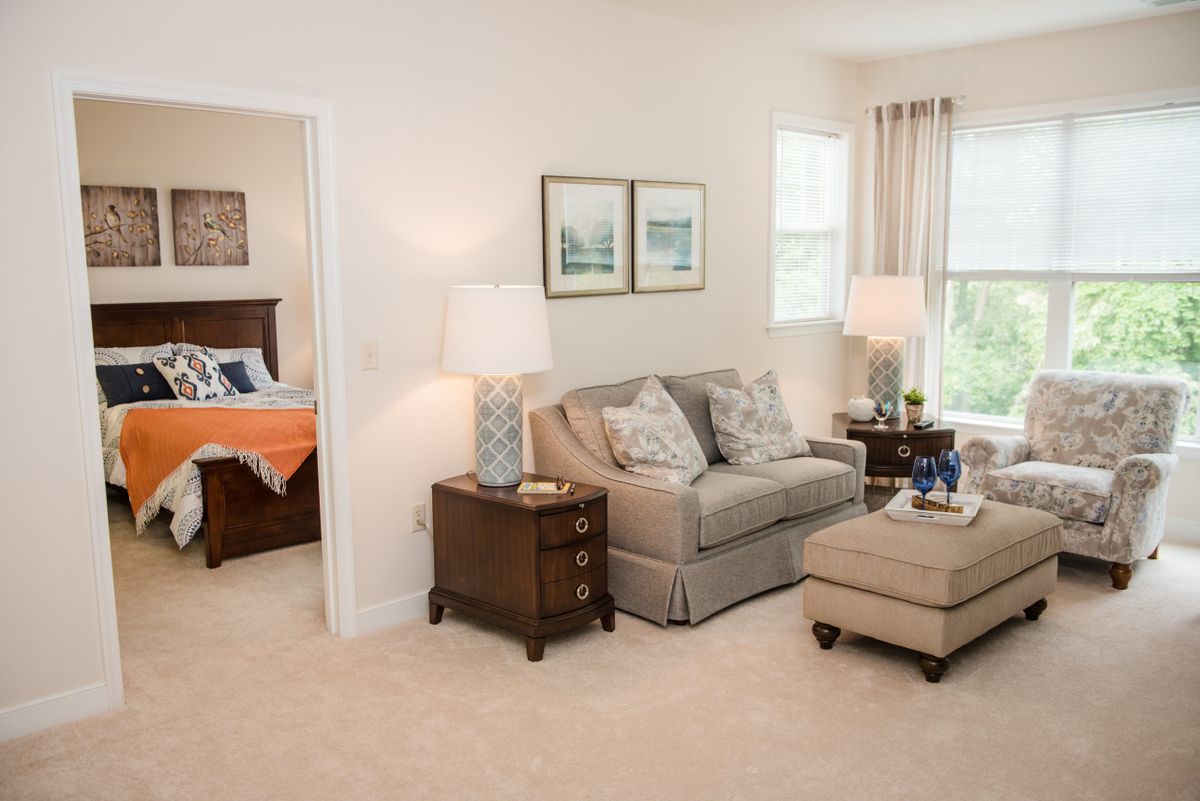 A cozy living room with a sofa, side tables, lamps, and decor items. The room is well-lit with natural light from the windows.