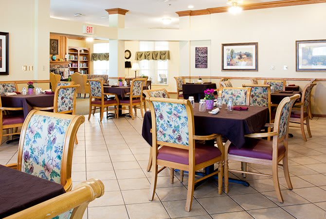 A cozy dining room with floral-patterned chairs and neatly set tables.
