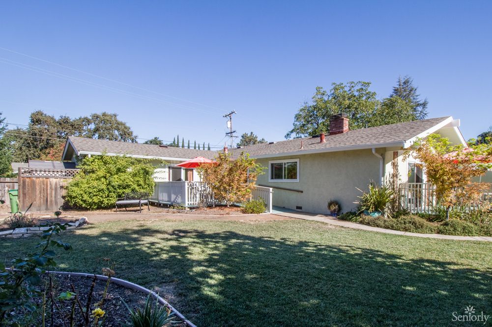 A sunny backyard with a well-maintained lawn and surrounding trees.