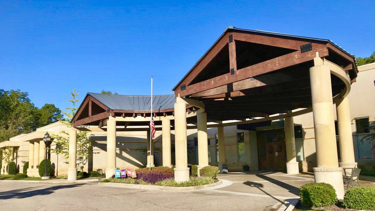 A building entrance with wooden beams and columns under a clear blue sky.
