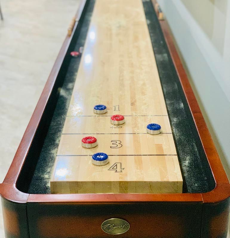 A shuffleboard table with red and blue pucks on the playing surface.