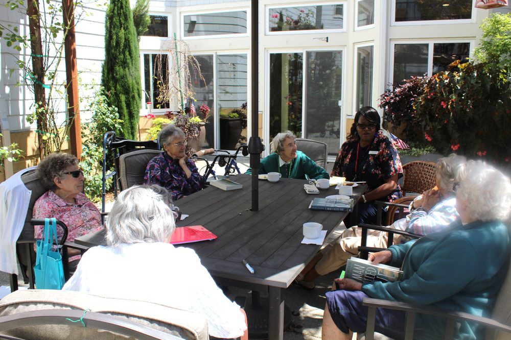 A group of elderly people sitting and socializing on a patio.