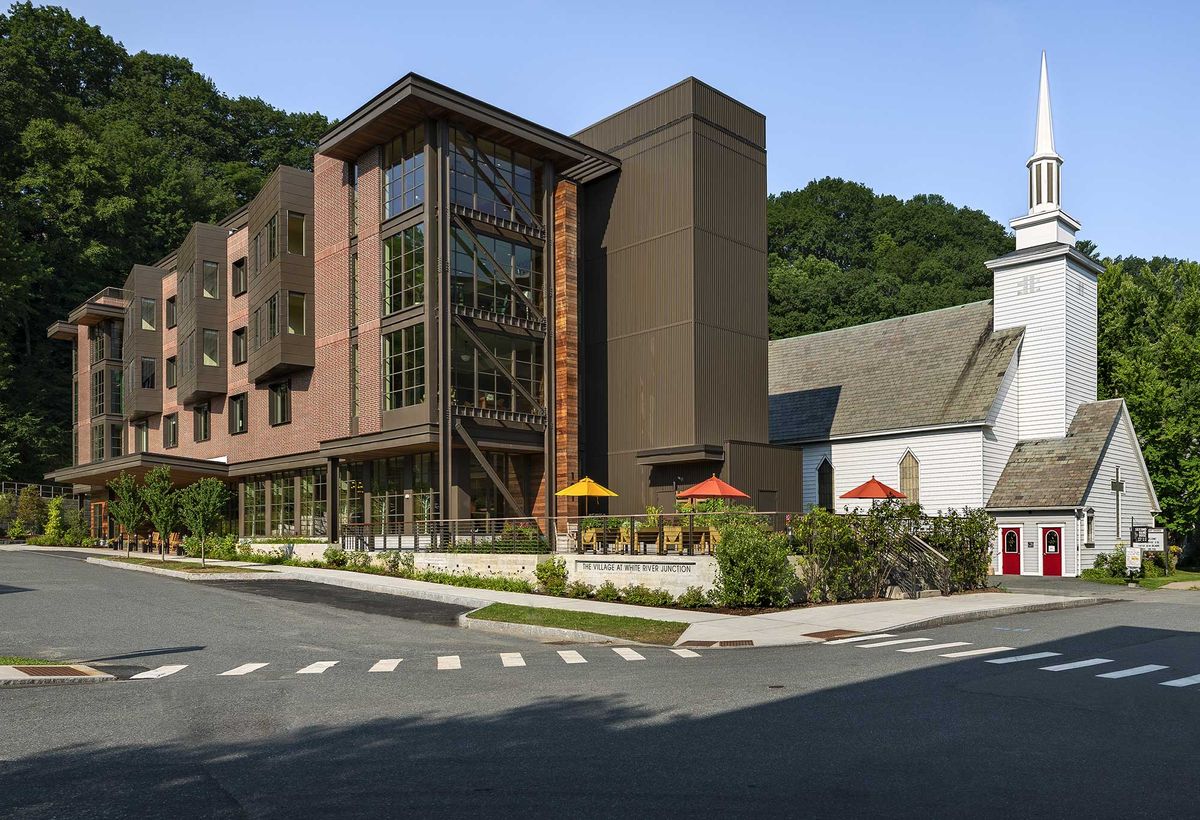 A modern building with outdoor seating and lush greenery in an urban setting.