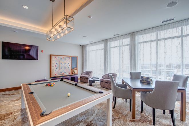 A modern game room featuring a pool table, stylish seating area, and contemporary decor.