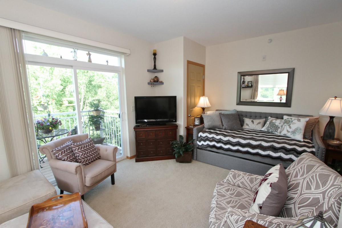 A cozy living room with a daybed, armchair, and TV, filled with natural light.