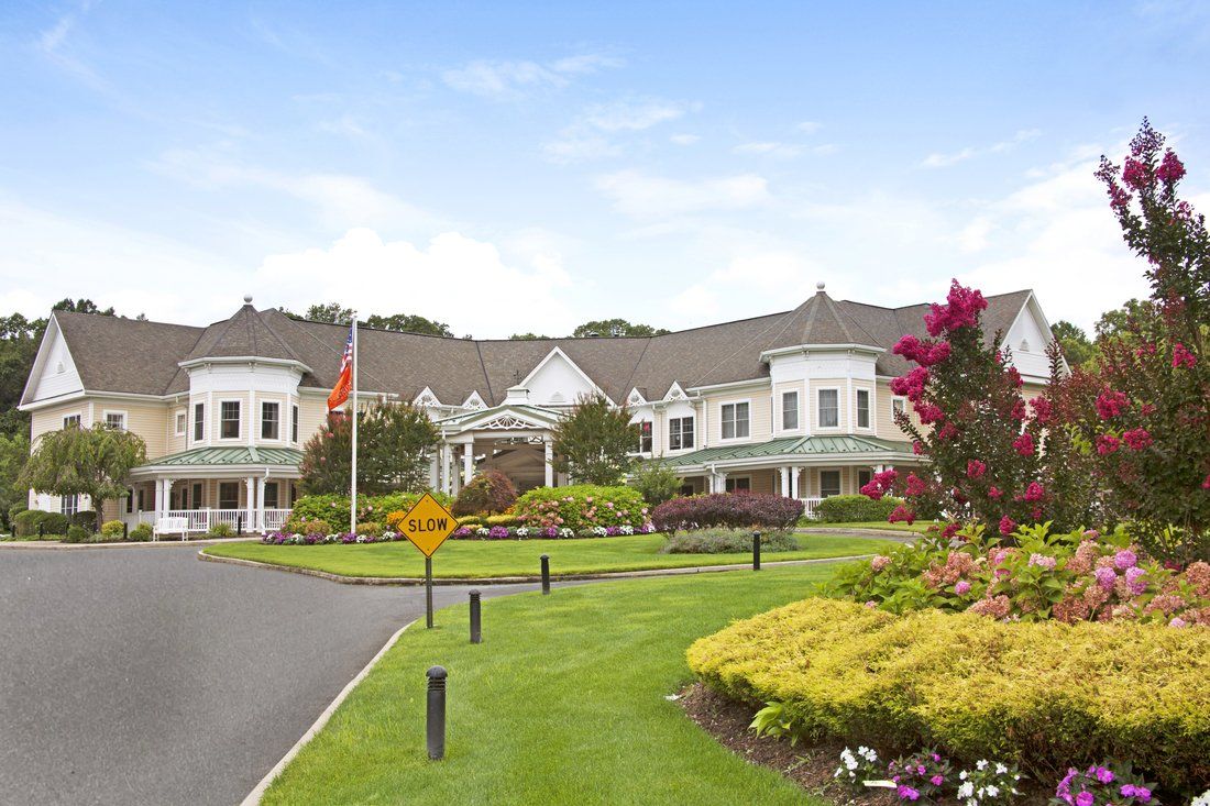 A luxurious building surrounded by beautifully manicured gardens and a driveway.