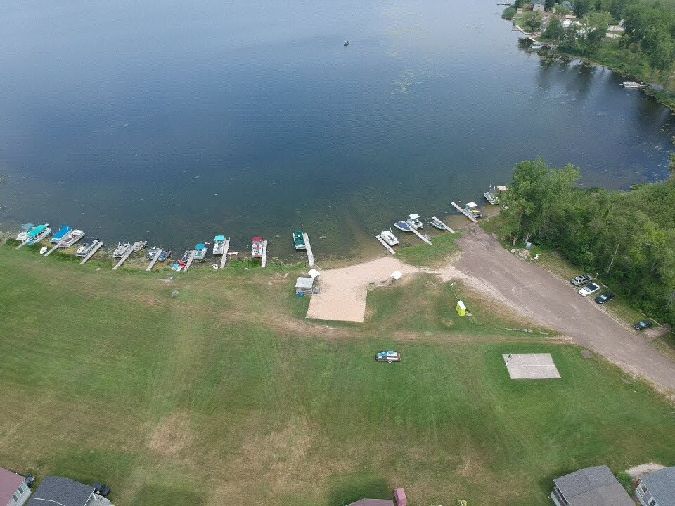 Aerial view of a lake with boats docked along the shoreline and a grassy area nearby.