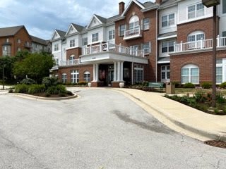 A multi-story residential building with a driveway and landscaped surroundings.