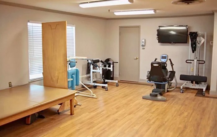 A compact fitness room with various exercise equipment and a wall-mounted TV.