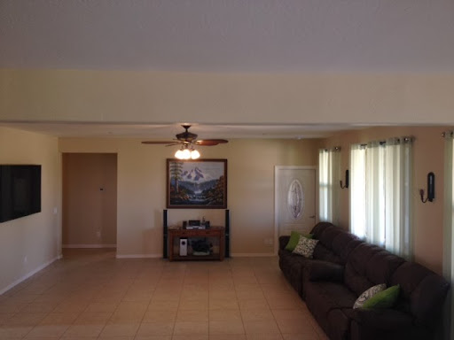 A spacious living room featuring a comfortable sofa, ceiling fan, and ample natural light.