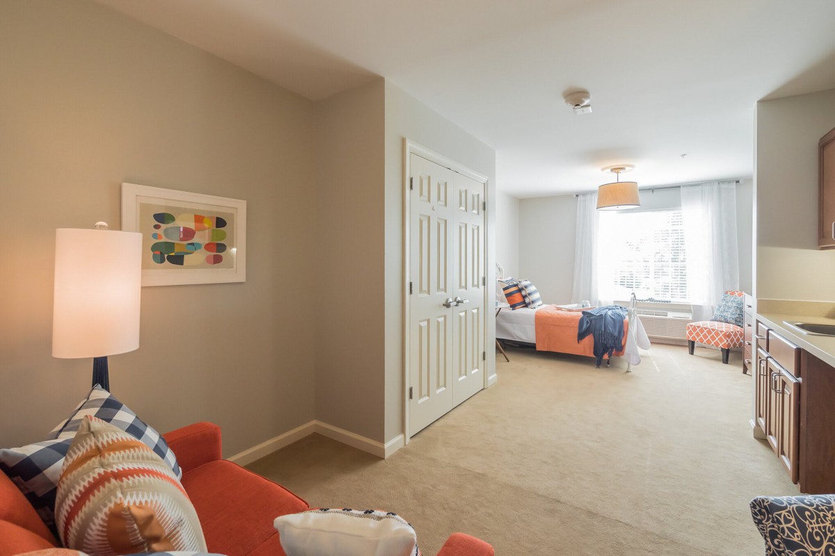 A cozy bedroom with a bed, closet, and natural light from a large window.