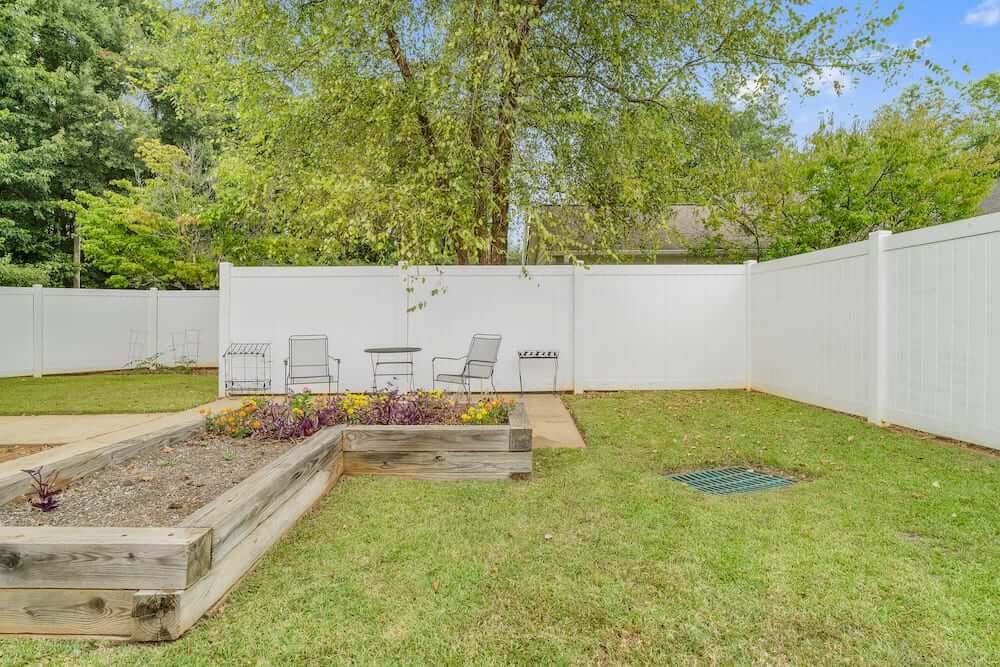 A peaceful backyard with a small patio, seating area, and surrounding trees.