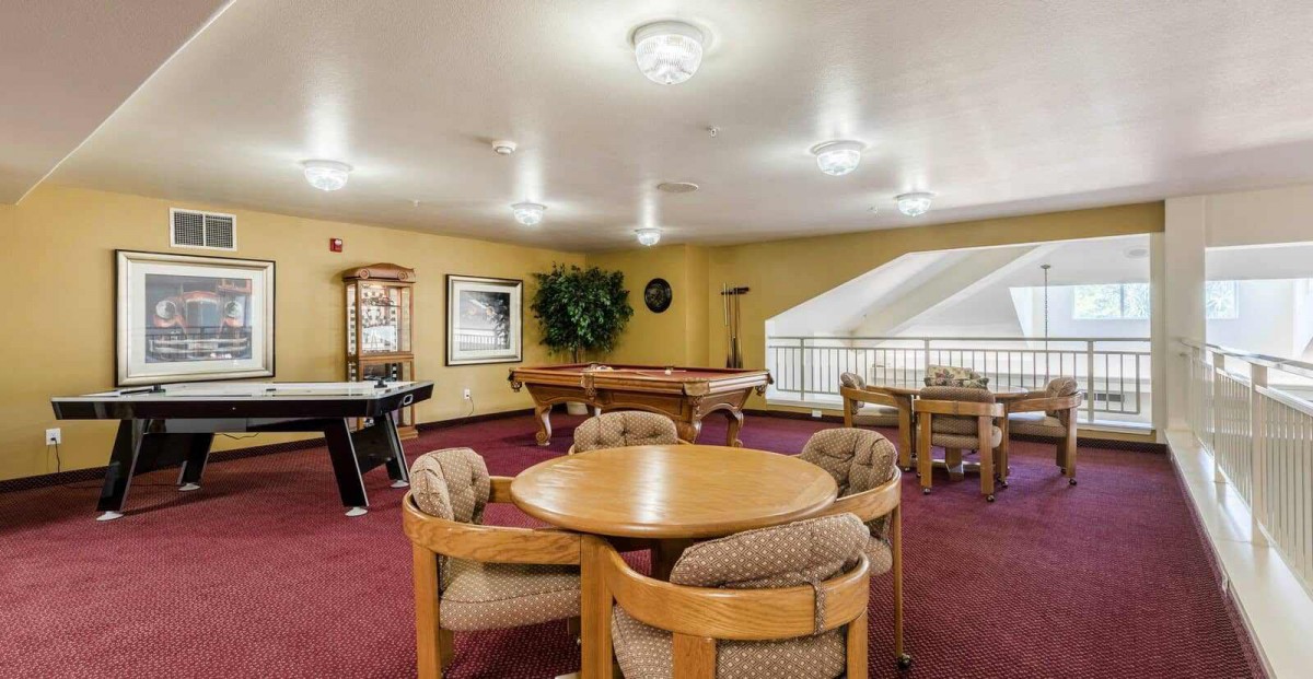 A spacious game room featuring pool and foosball tables with seating arrangements.