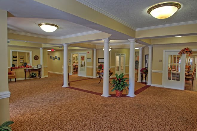 A lobby area with carpeted floors, white columns, and decorative lighting.