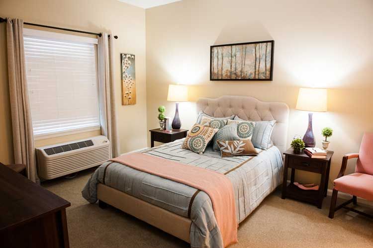A cozy bedroom with a neatly made bed, soft lighting from lamps, and wall artwork.