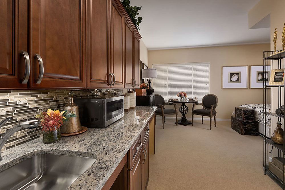 A modern kitchen with wood cabinets and granite countertops, leading to a cozy dining area.
