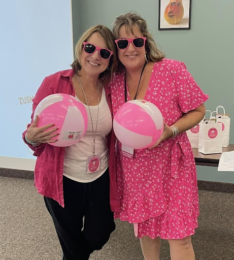 Two friends enjoying a fun day with beach balls, dressed in vibrant pink outfits and sunglasses.
