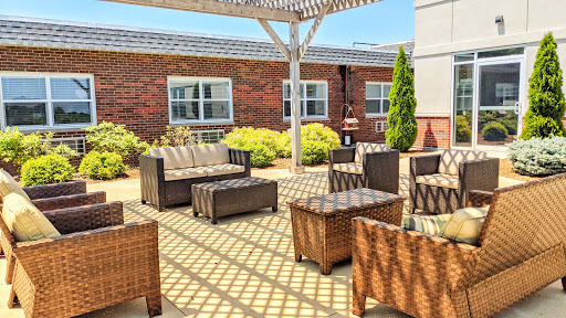 A cozy outdoor seating area featuring modern wicker furniture under a sunshade.